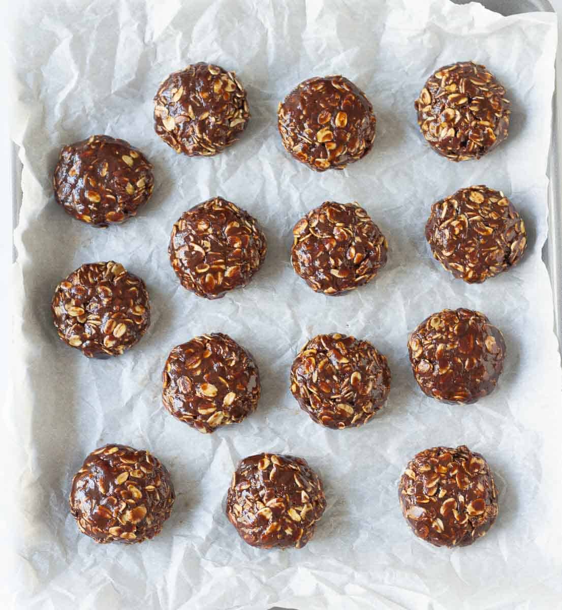 cookie dough shaped into balls on parchment paper.