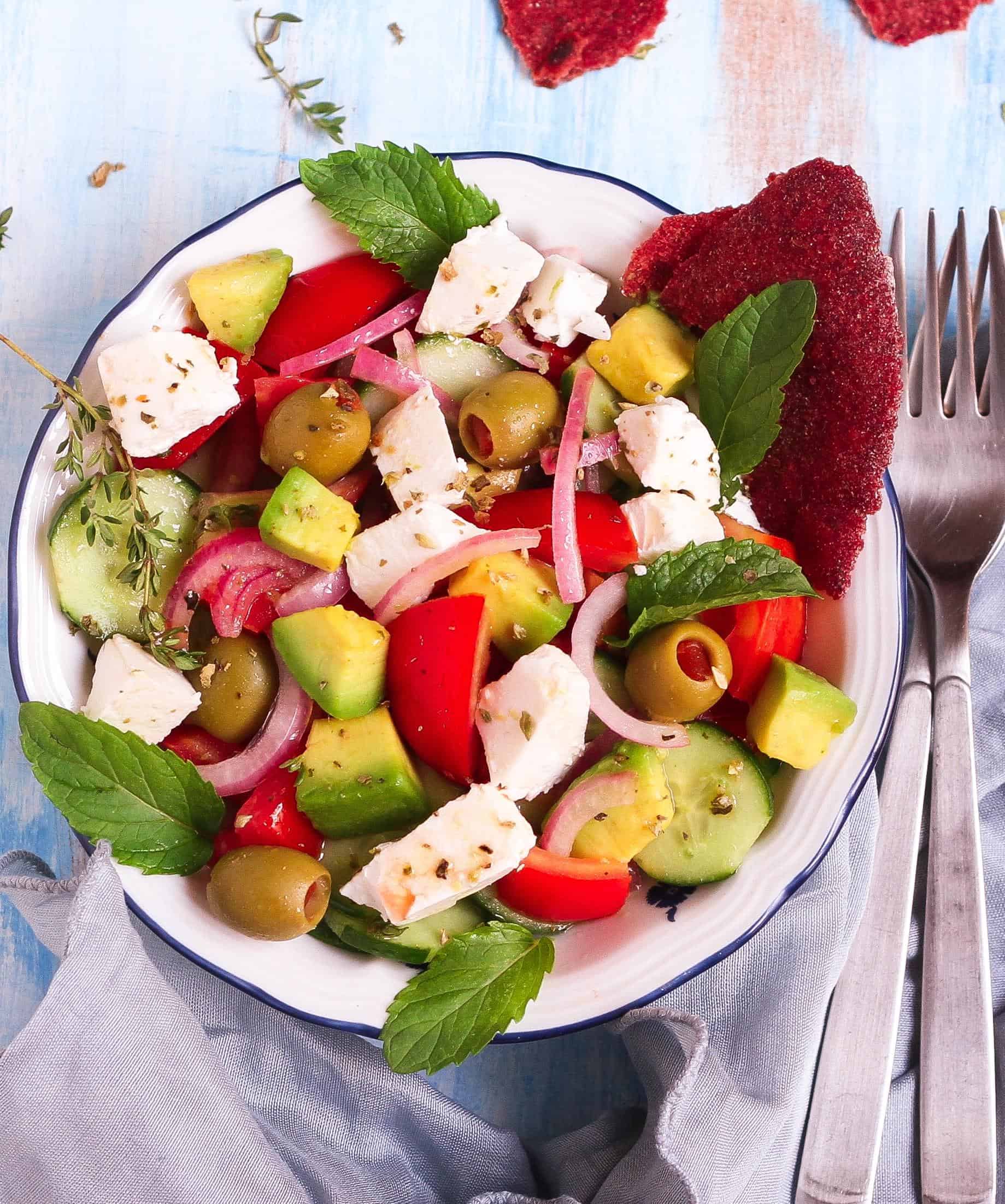 Greek salad in a bowl with 2 forks on the side.