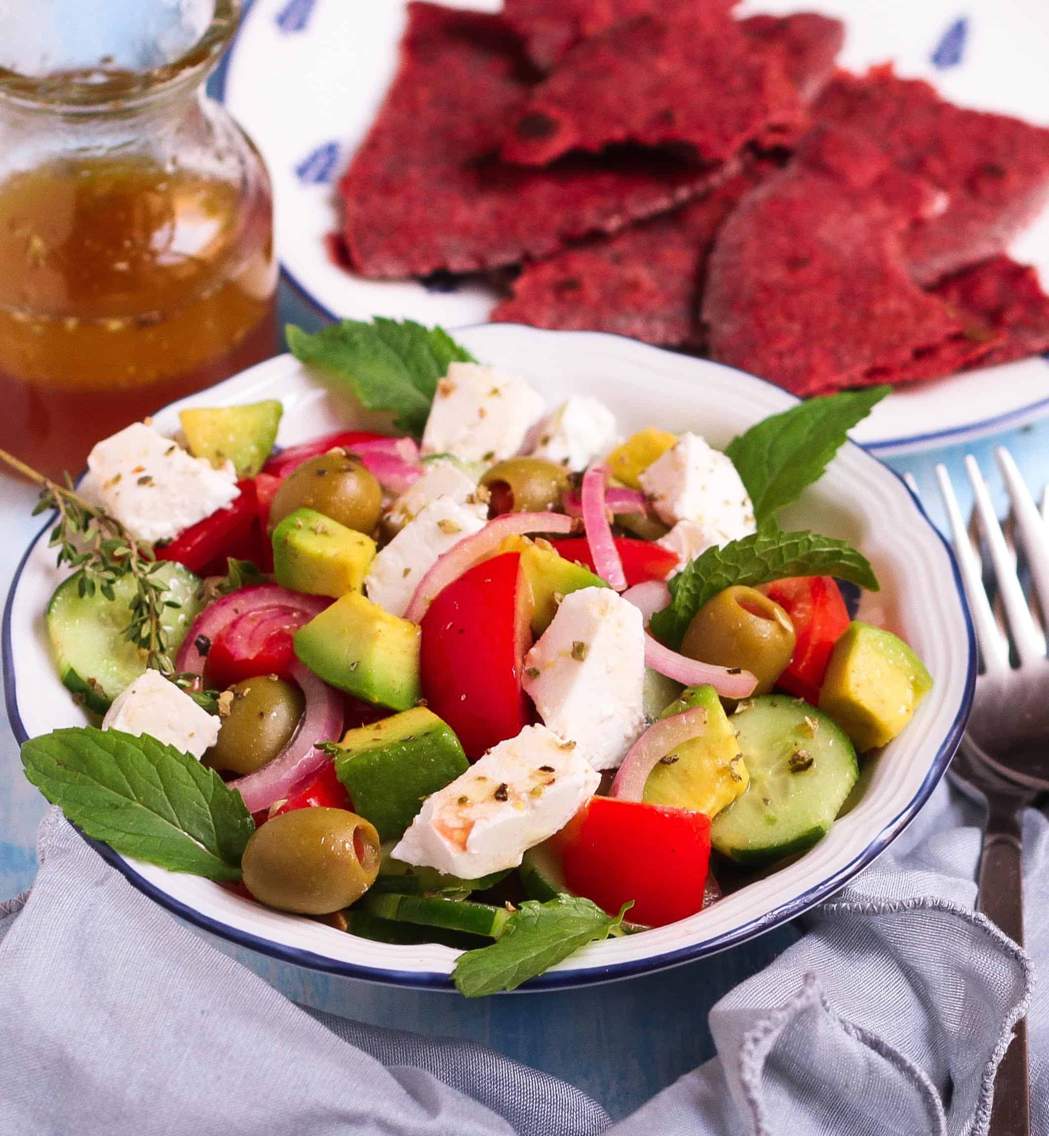 Easy Greek Salad in a bowl with ingredients in the background.