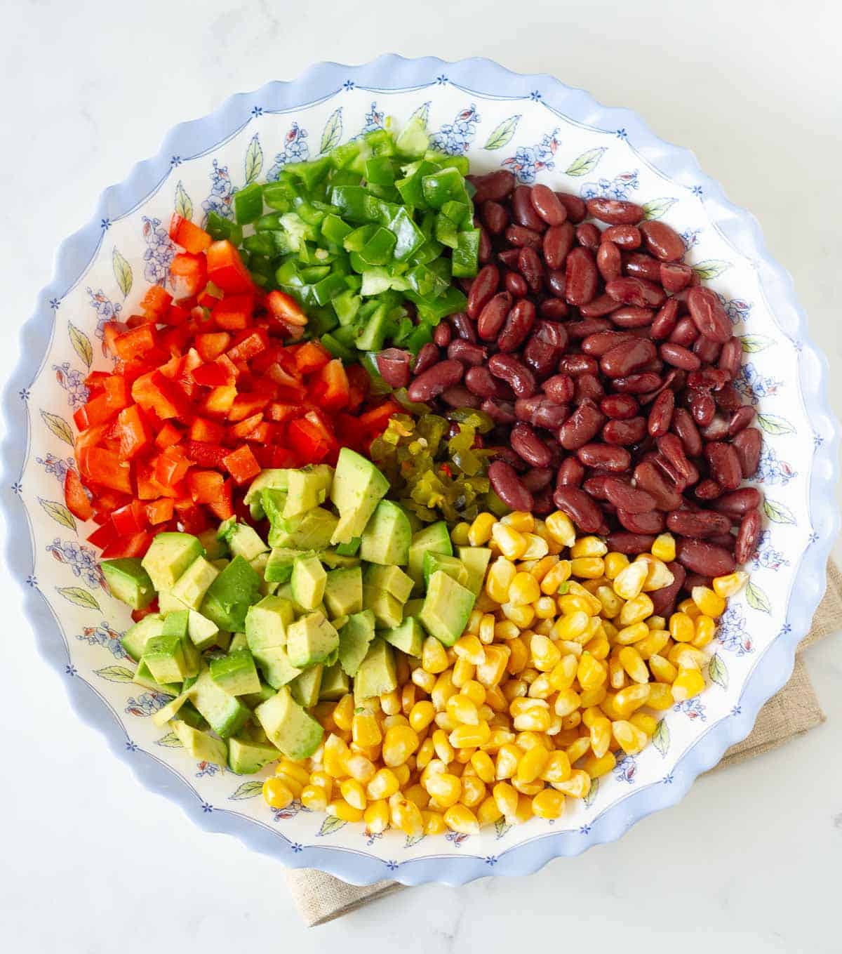 Chopped bell peppers, avocado, corn, and beans in a bowl.