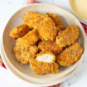 A bowl of chicken nuggets with one nugget cut in half.