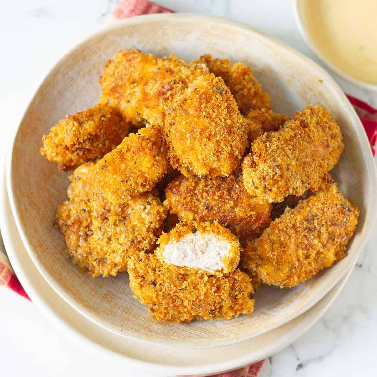 A bowl of chicken nuggets with one nugget cut in half.