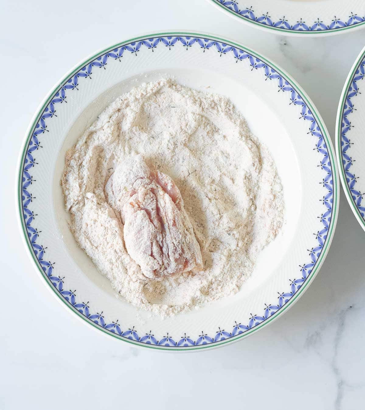 one chicken piece coated in flour in a bowl.