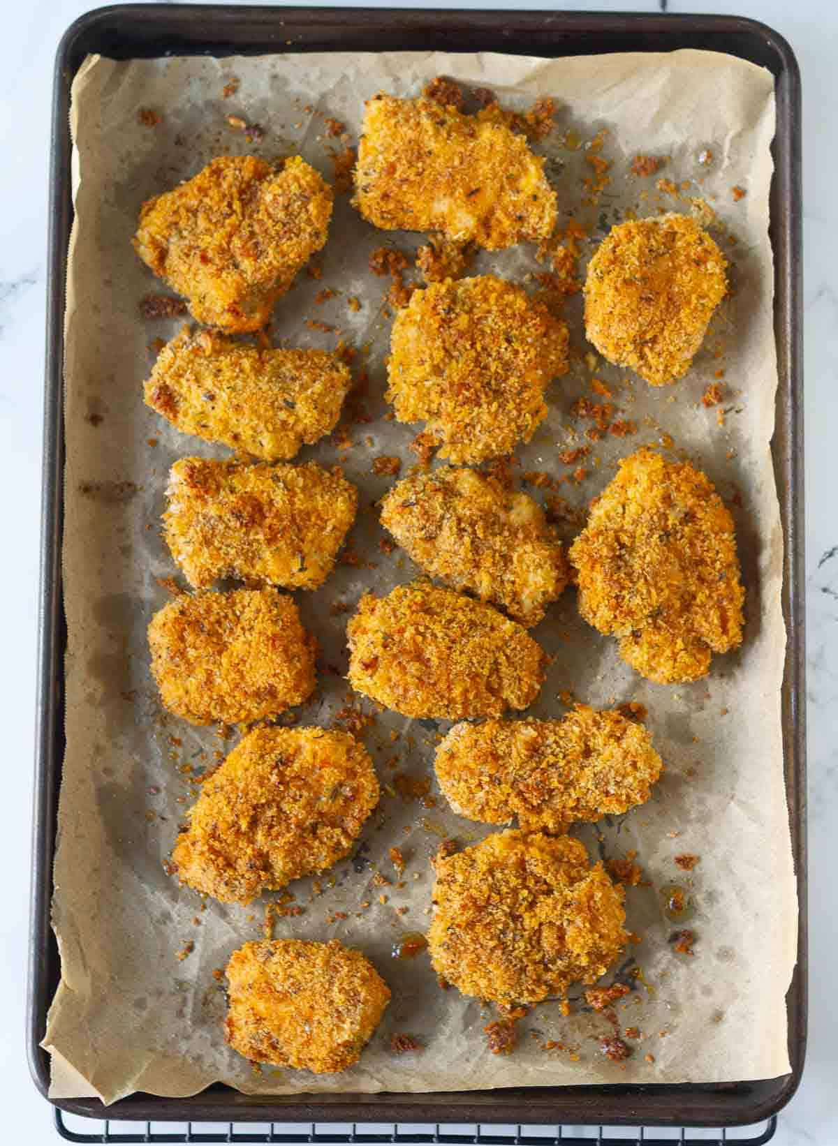 Baked chicken nuggets on a parchment-lined tray.
