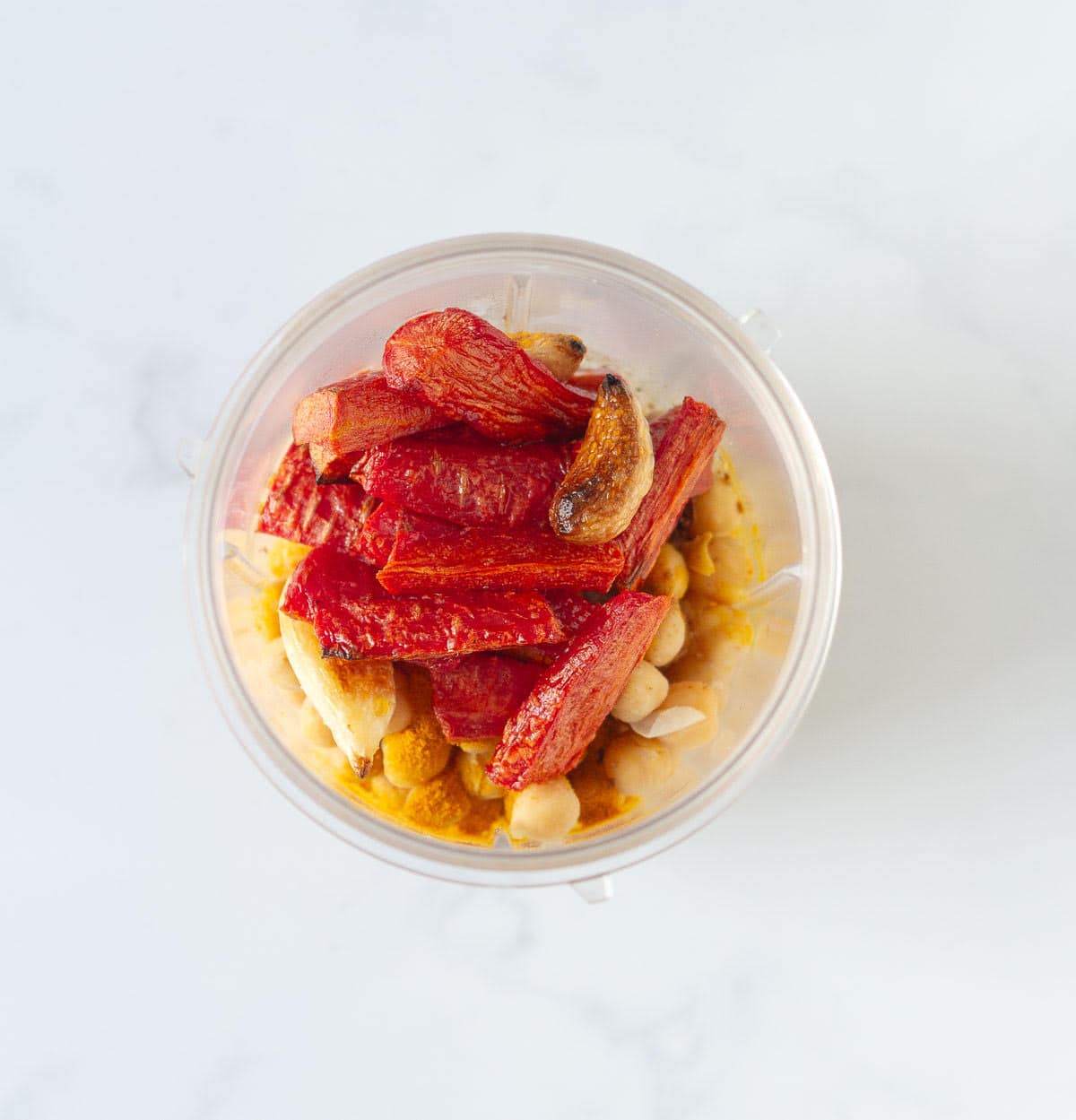 Roasted carrots, garlic, chickpeas, and spices in a blender jar.