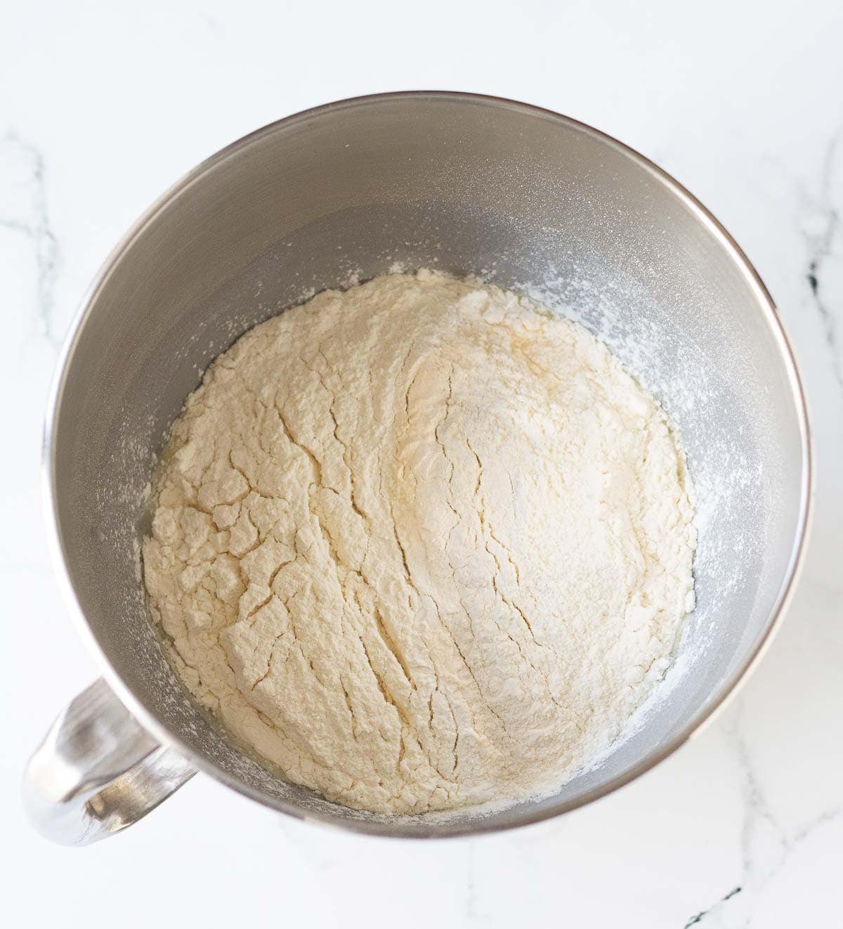 Flour on top of the liquid mixture ina mixing bowl.