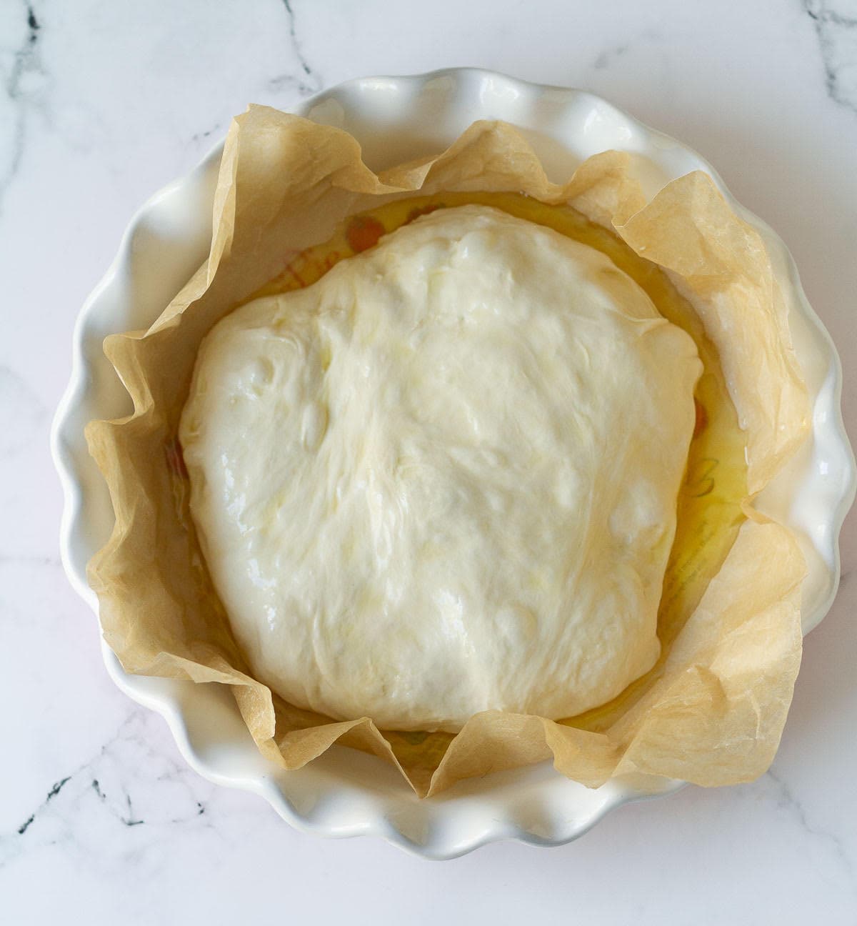 Dough in a parchment-lined round baking dish.