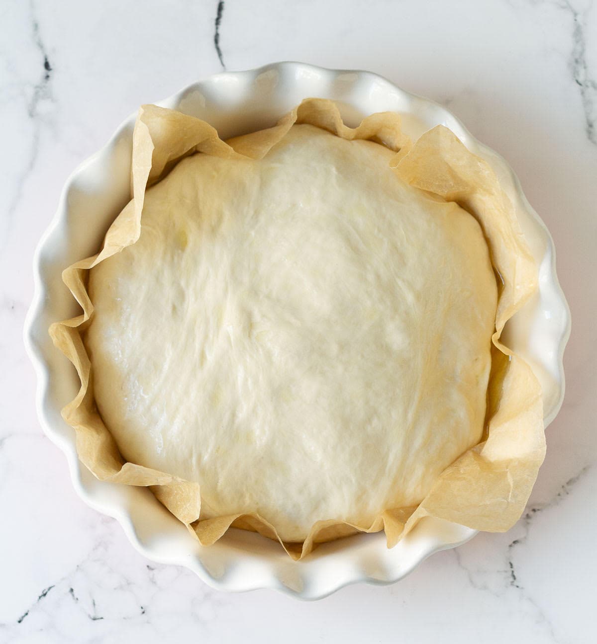 Proofed dough in a parchment-lined baking dish.