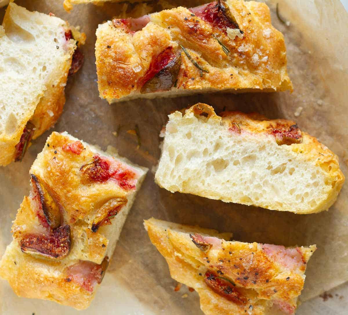 Slices of focaccia with figs on parchment paper.