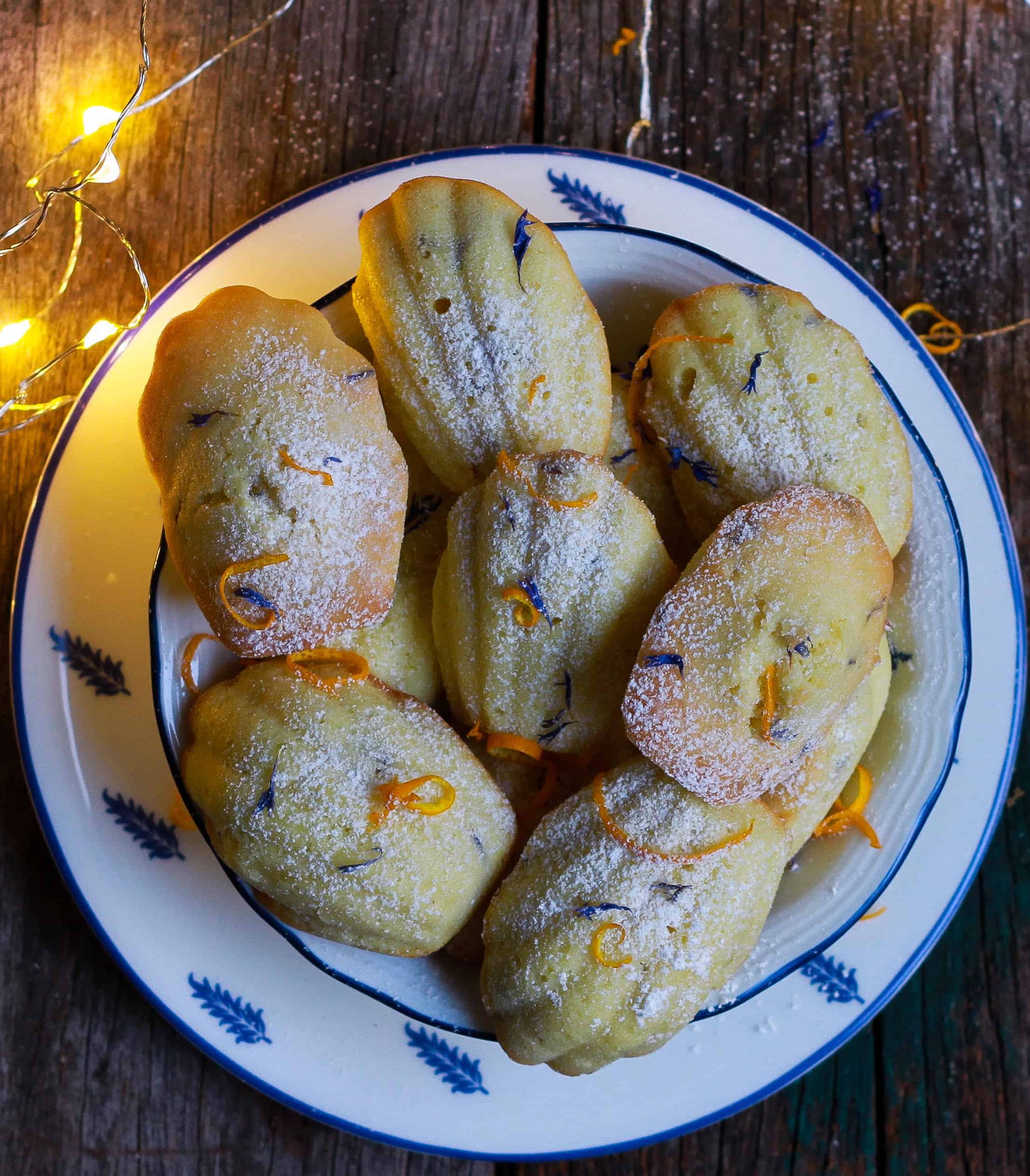 Orange Madeleines w/ dried blue cornflowers in a bowl.