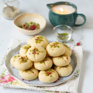 A stack of cookies on a plate with candle and ingredients around.