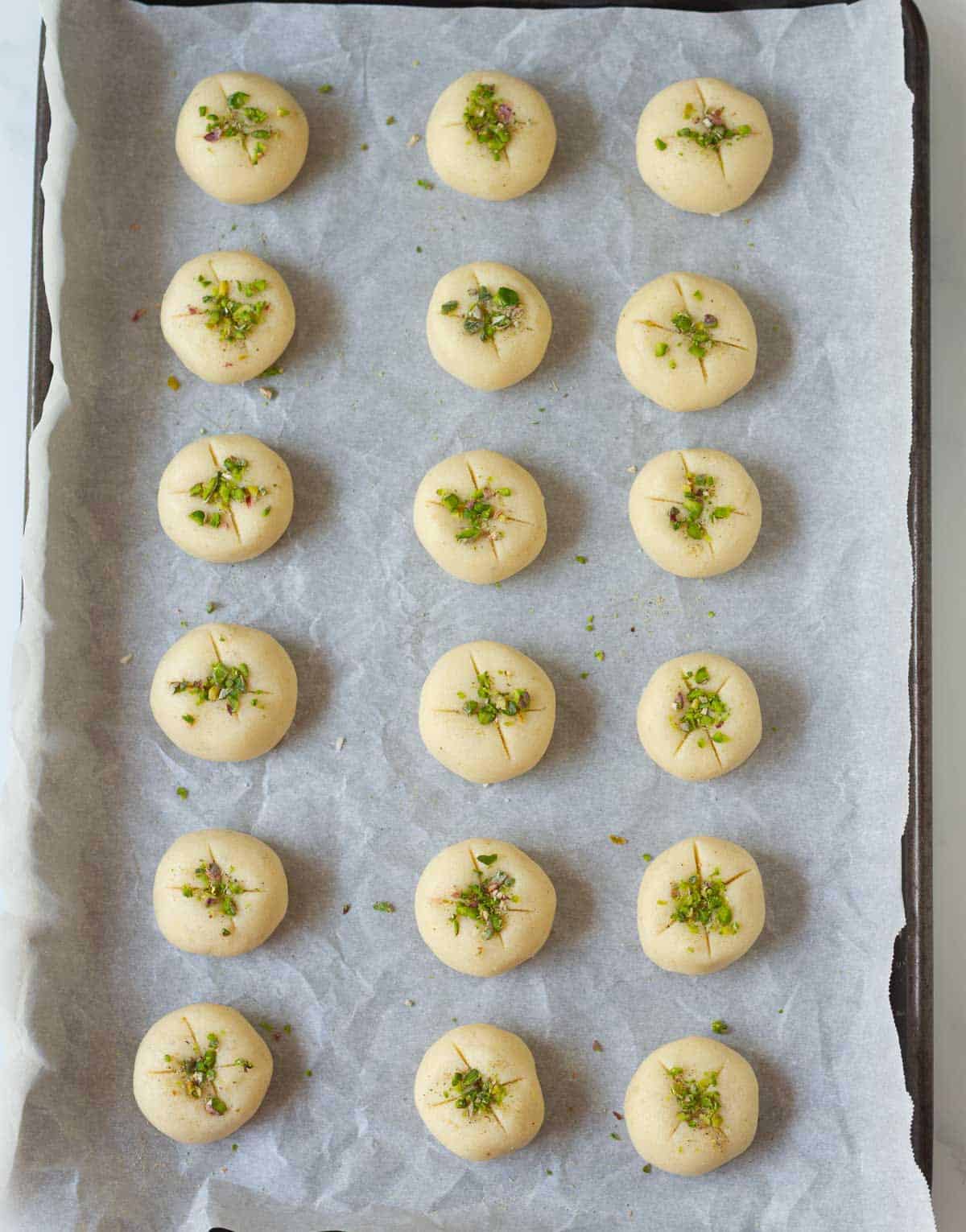 Cookie dough balls with criss cross cut and chopped pistachios on top.