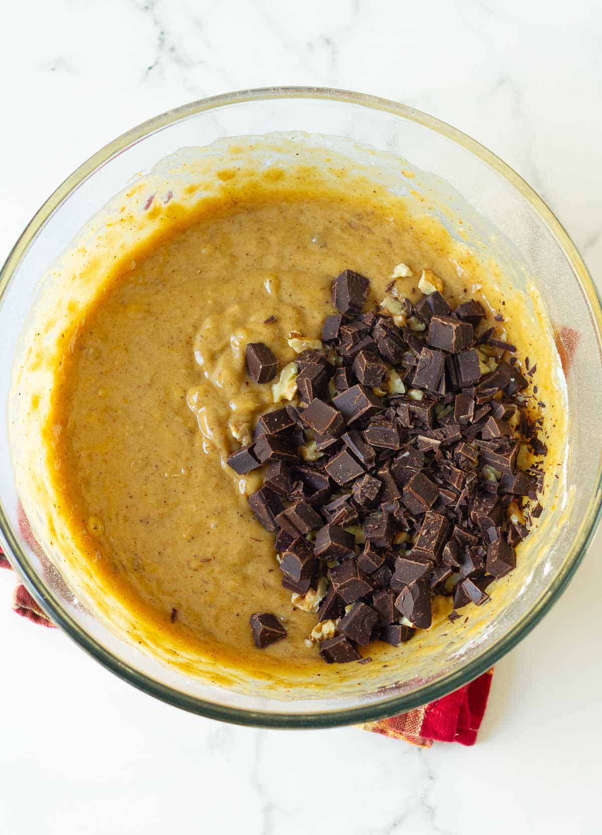 Chocolate chunks on top of cake batter in a bowl.