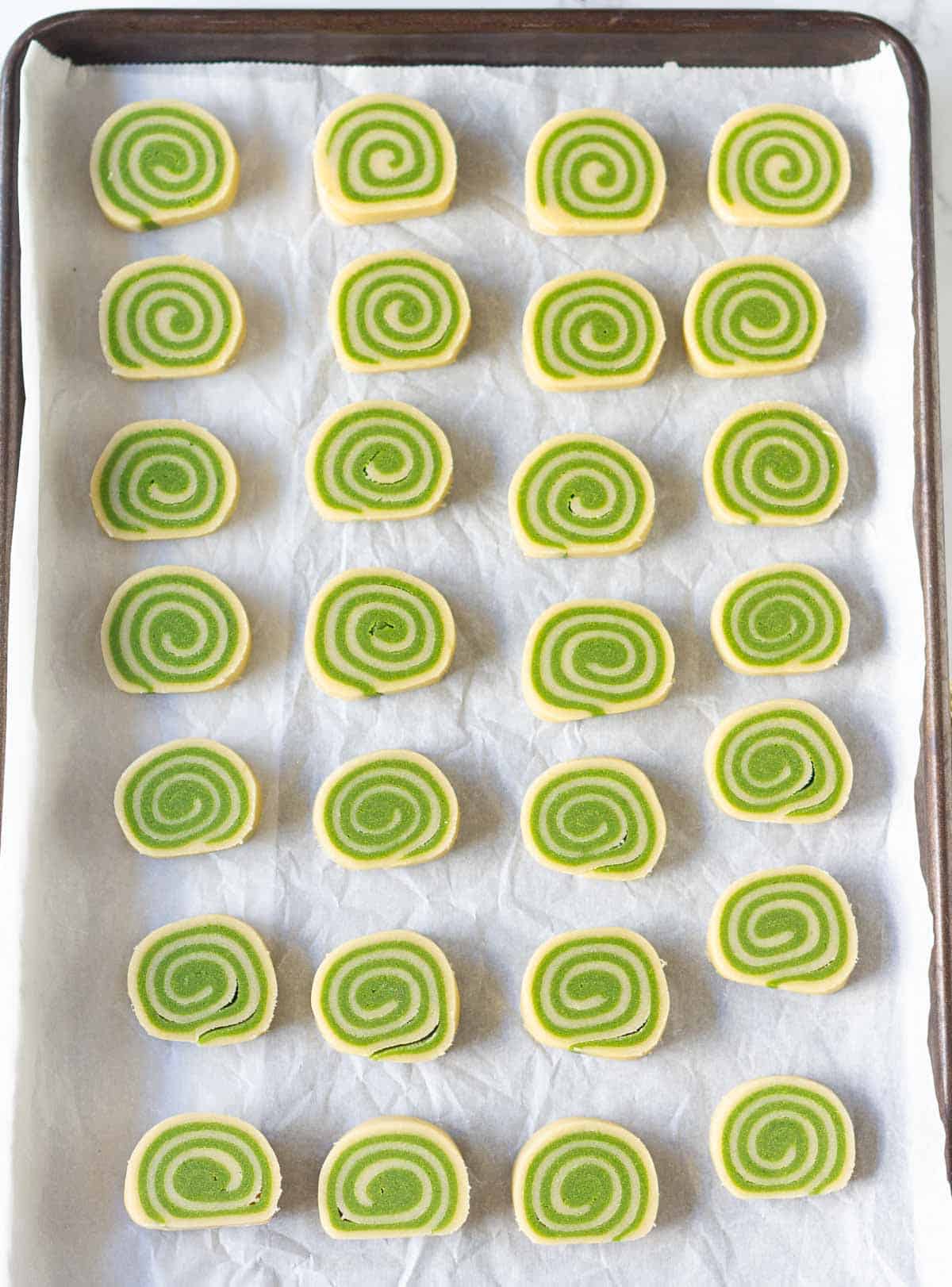 sliced cookie dough on parchment-lined baking tray.