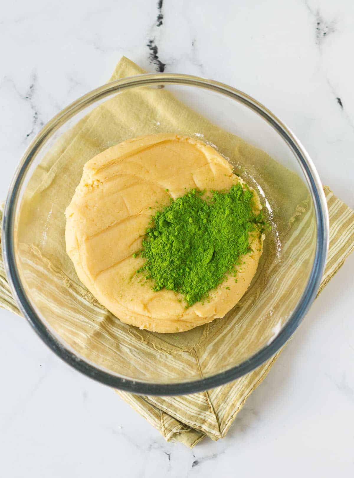 matcha powder on cookie dough in a mixing bowl.