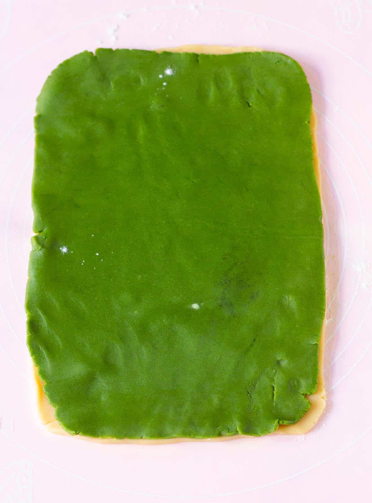 vanilla and matcha cookie doughs rolled out and placed on top of each other.