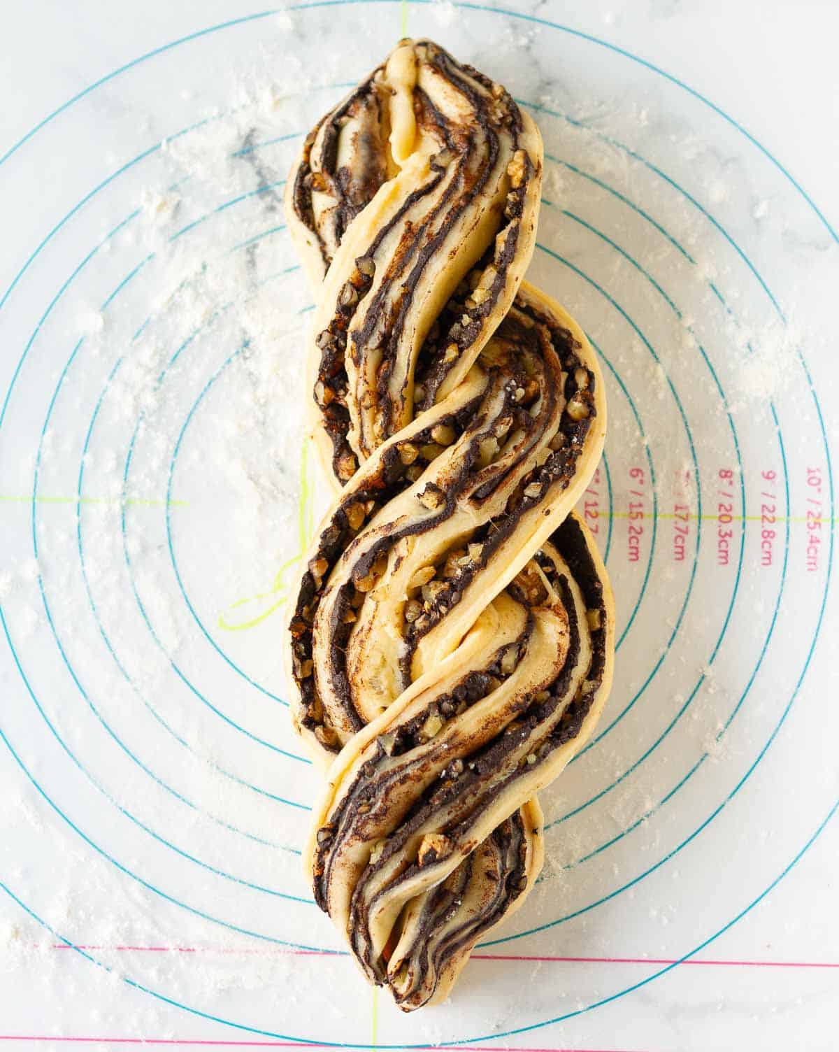two dough halves braided together on a silicon mat.
