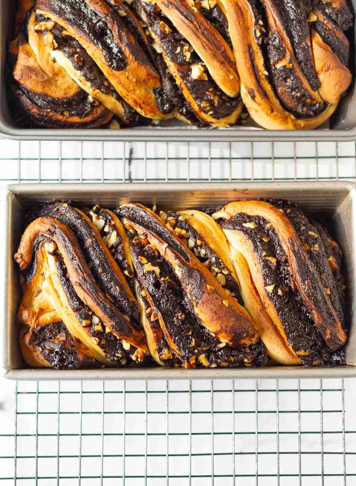 baked chocolate babkas in 2 loaf pans on a wire rack.
