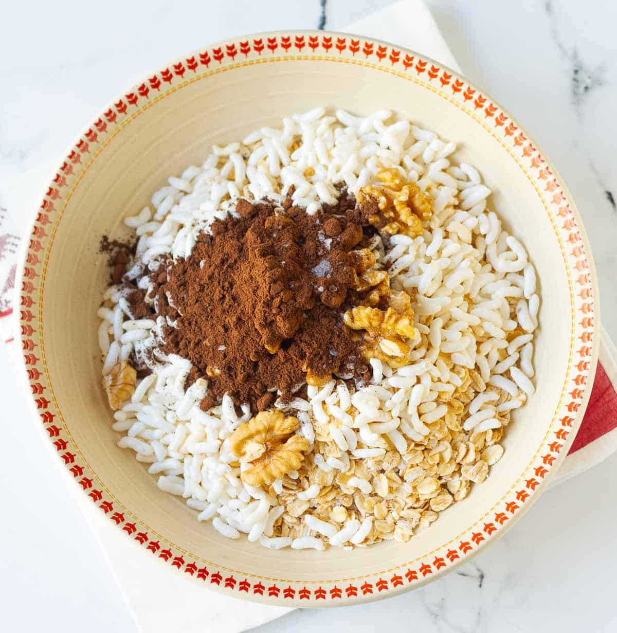 oats, puffed rice, walnuts,and cocoa powder in a bowl.