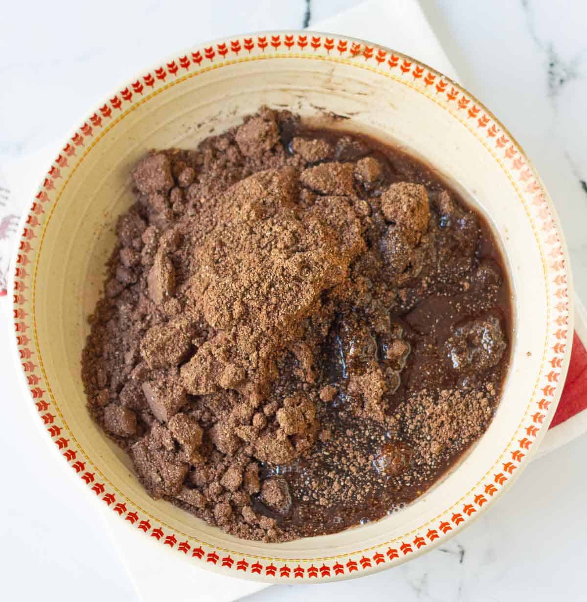 Coconut oil and maple syrup on top of dry ingredients in a bowl.