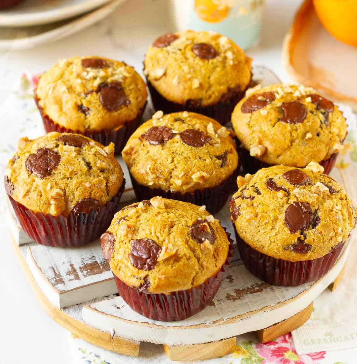 7 muffins with chocolate chips on top on a white tray.