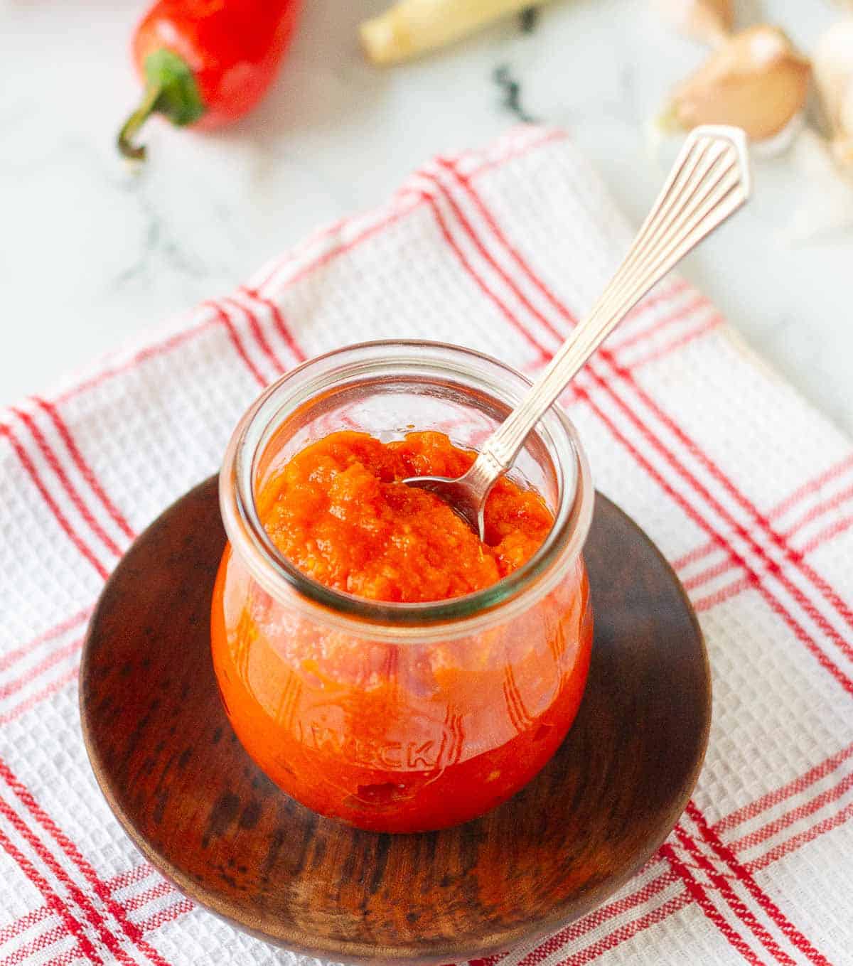 sambal oelek chili sauce in a glass jar with a spoon.