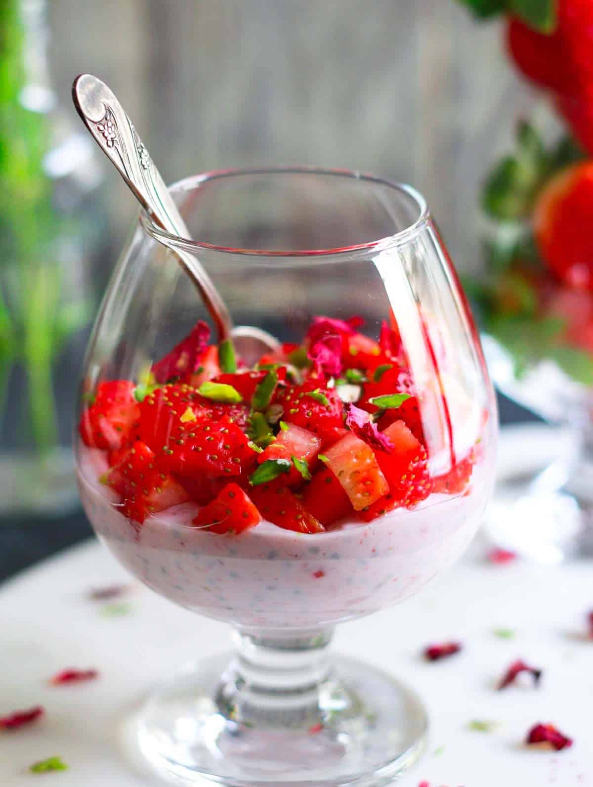 strawberry rose chia pudding in a dessert glass with a spoon.