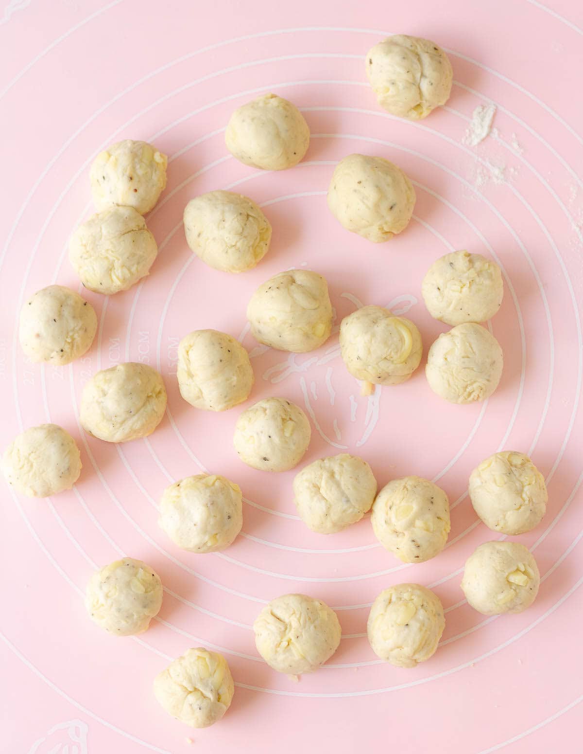 Bread dough rolled into small balls on a silicone mat.