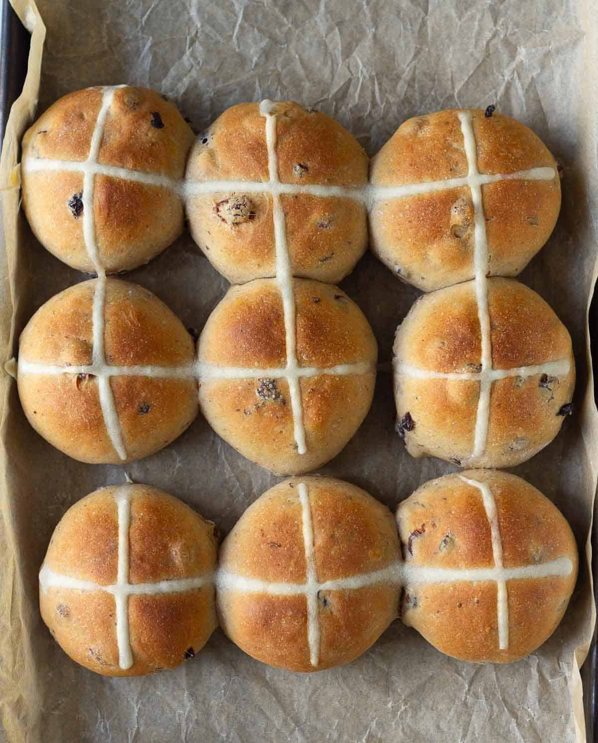 Baked hot cross buns on a paper-liner tray.