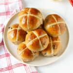 Vegan hot cross buns placed on plate with a napkin on the side.