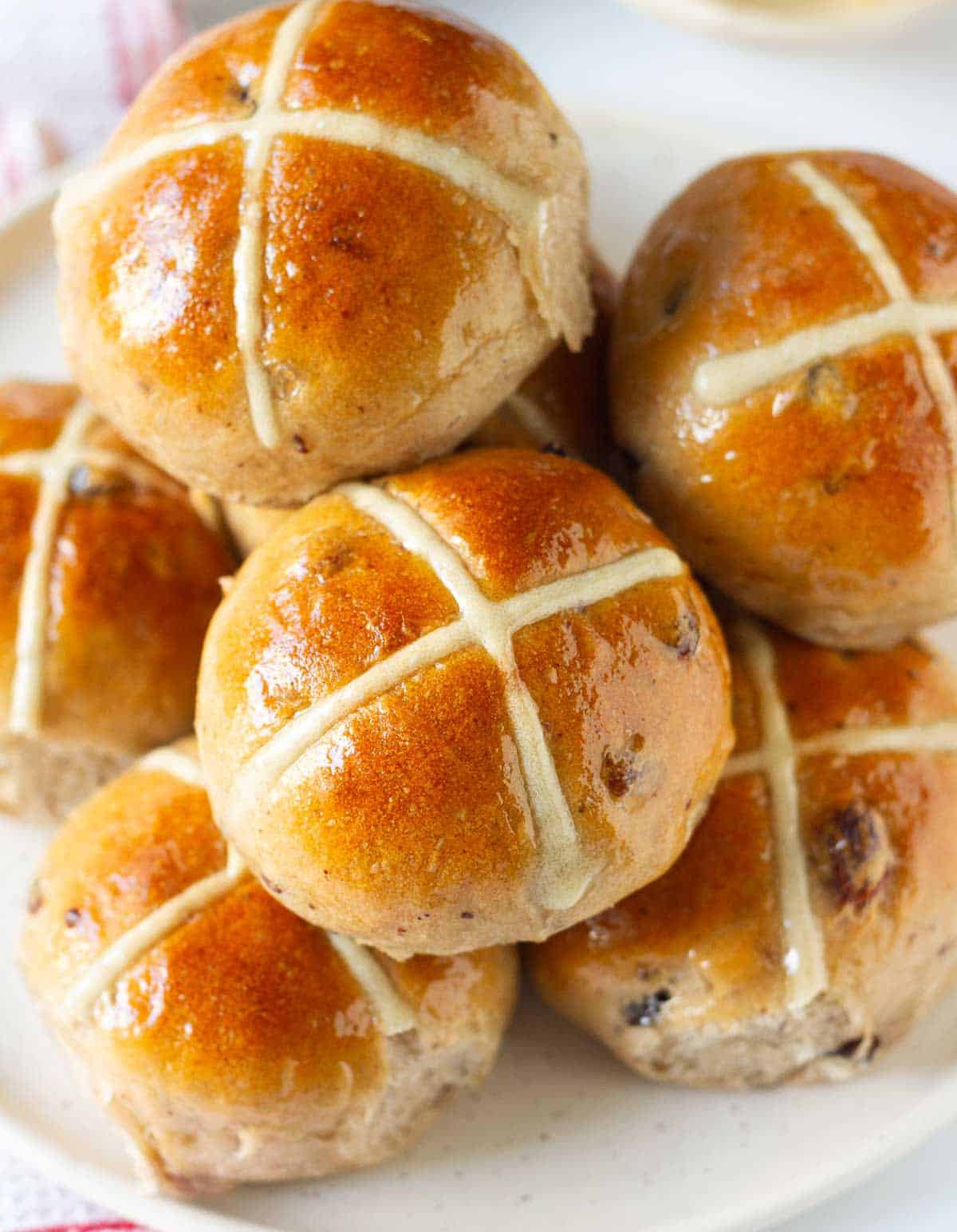 Hot cross buns stacked up on a plate.