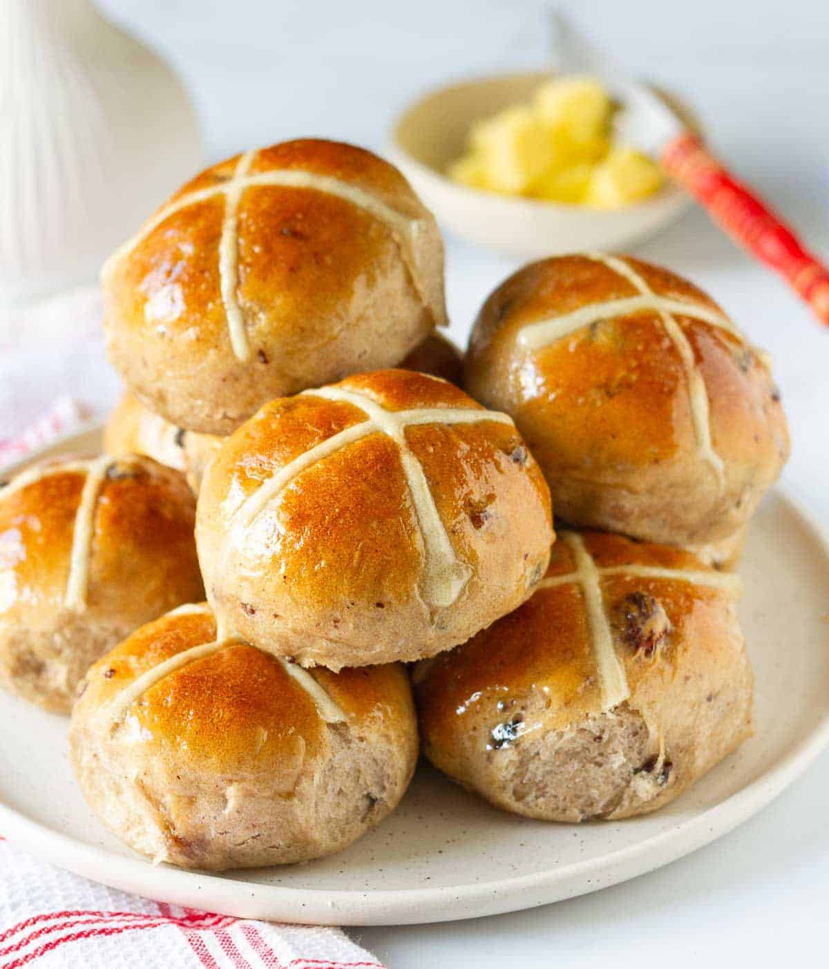 Hot cross buns stacked up on a plate.