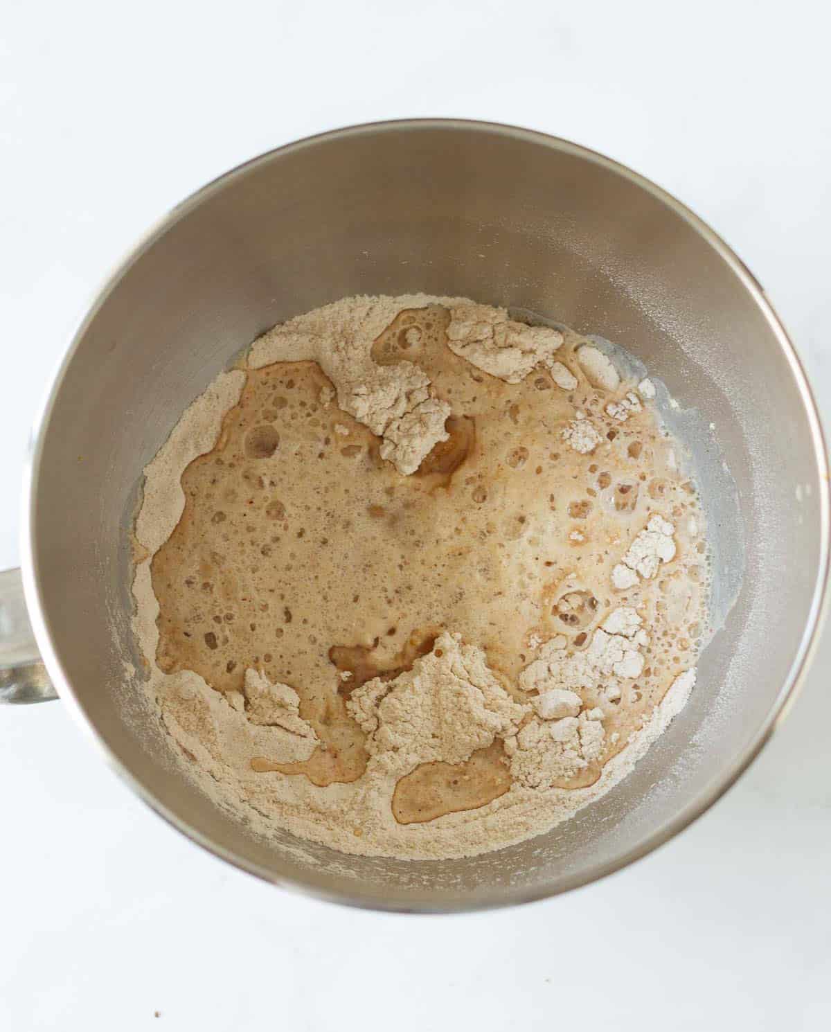 Yeast mixture on top of the dry ingredients in a mixer bowl.