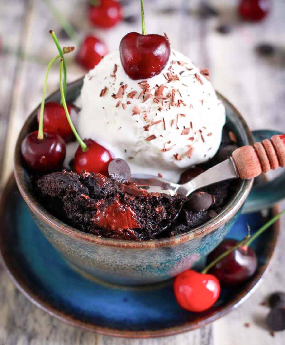 Mug cake with vanilla ice cream and bite taken out in a spoon.