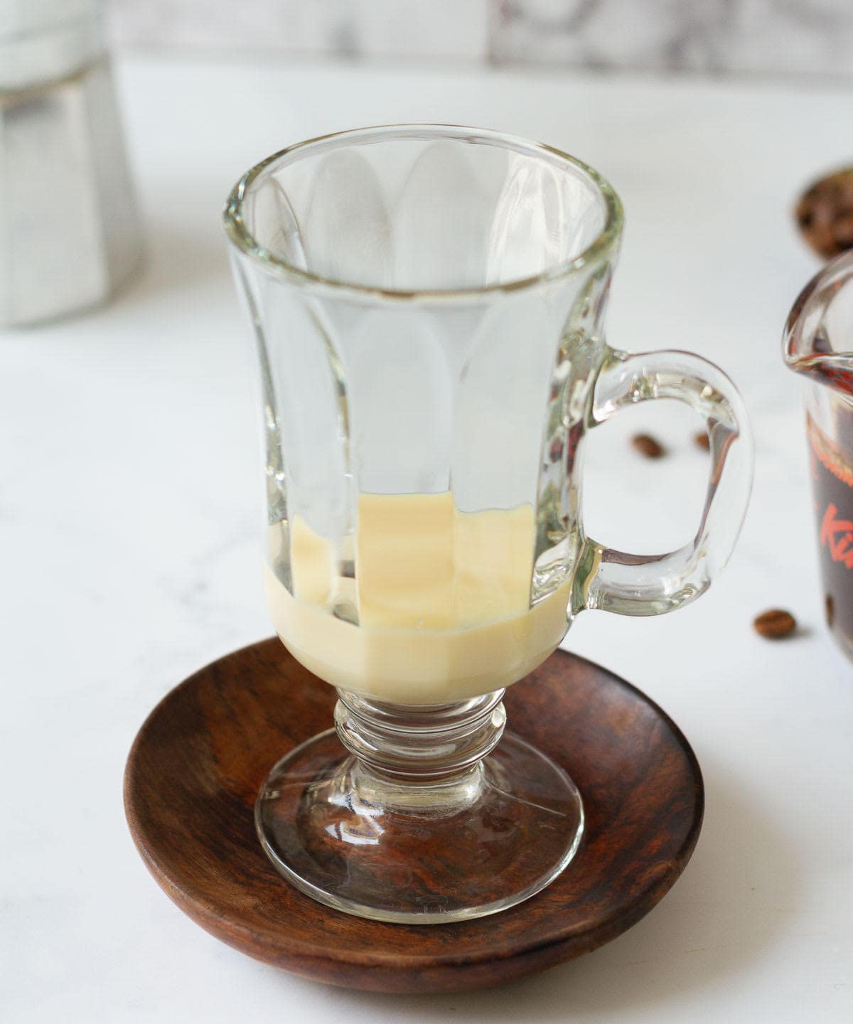 Sweetened condensed milk in a cup placed on a wooden saucer.
