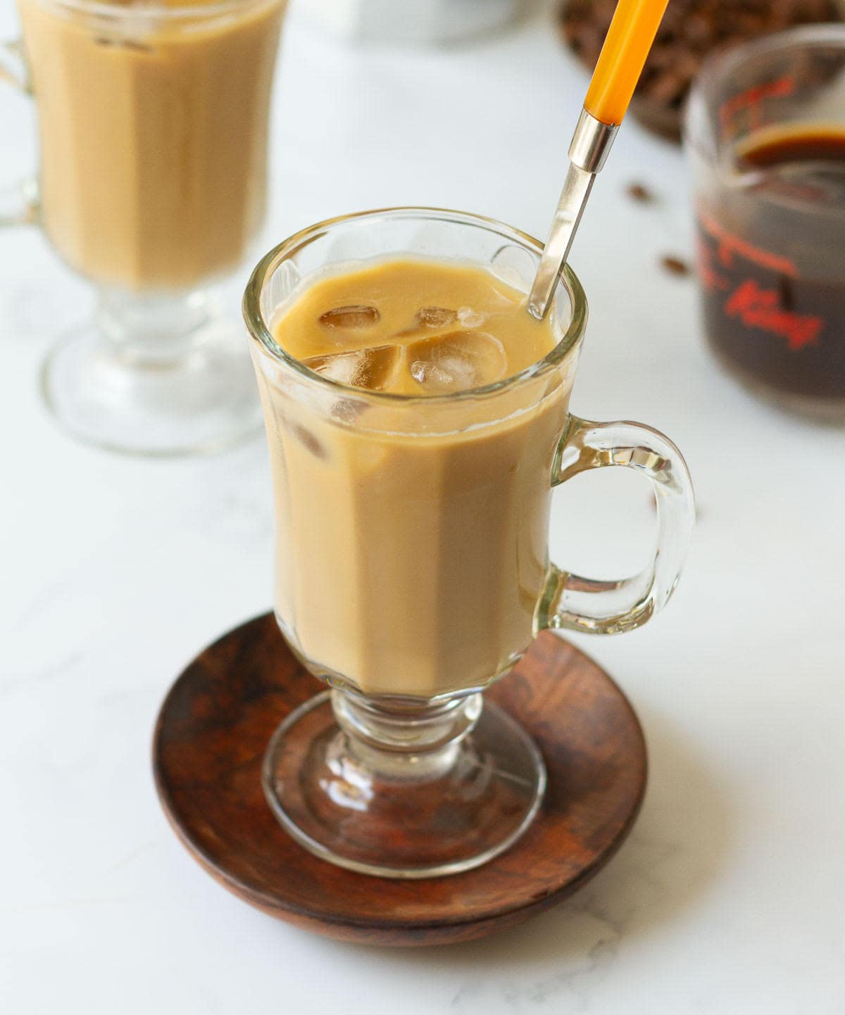 Iced coffee in a cup with an orange spoon.