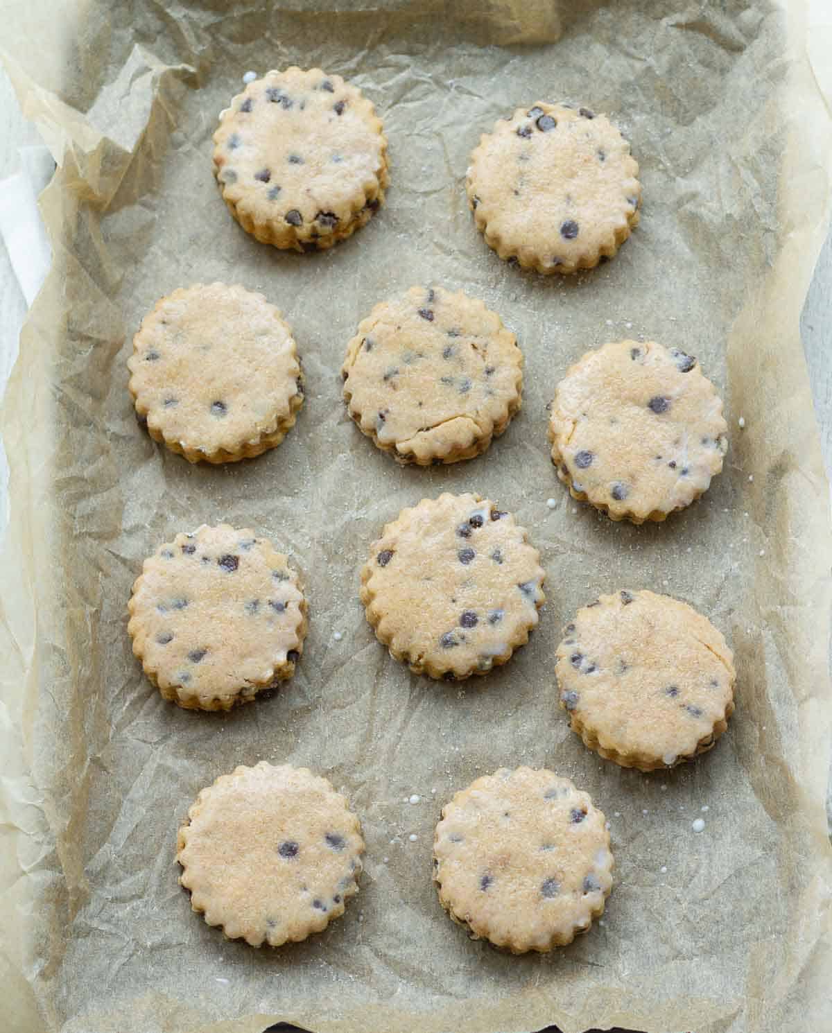 Shaped scones brushed with milk on a parchment-lined tray.