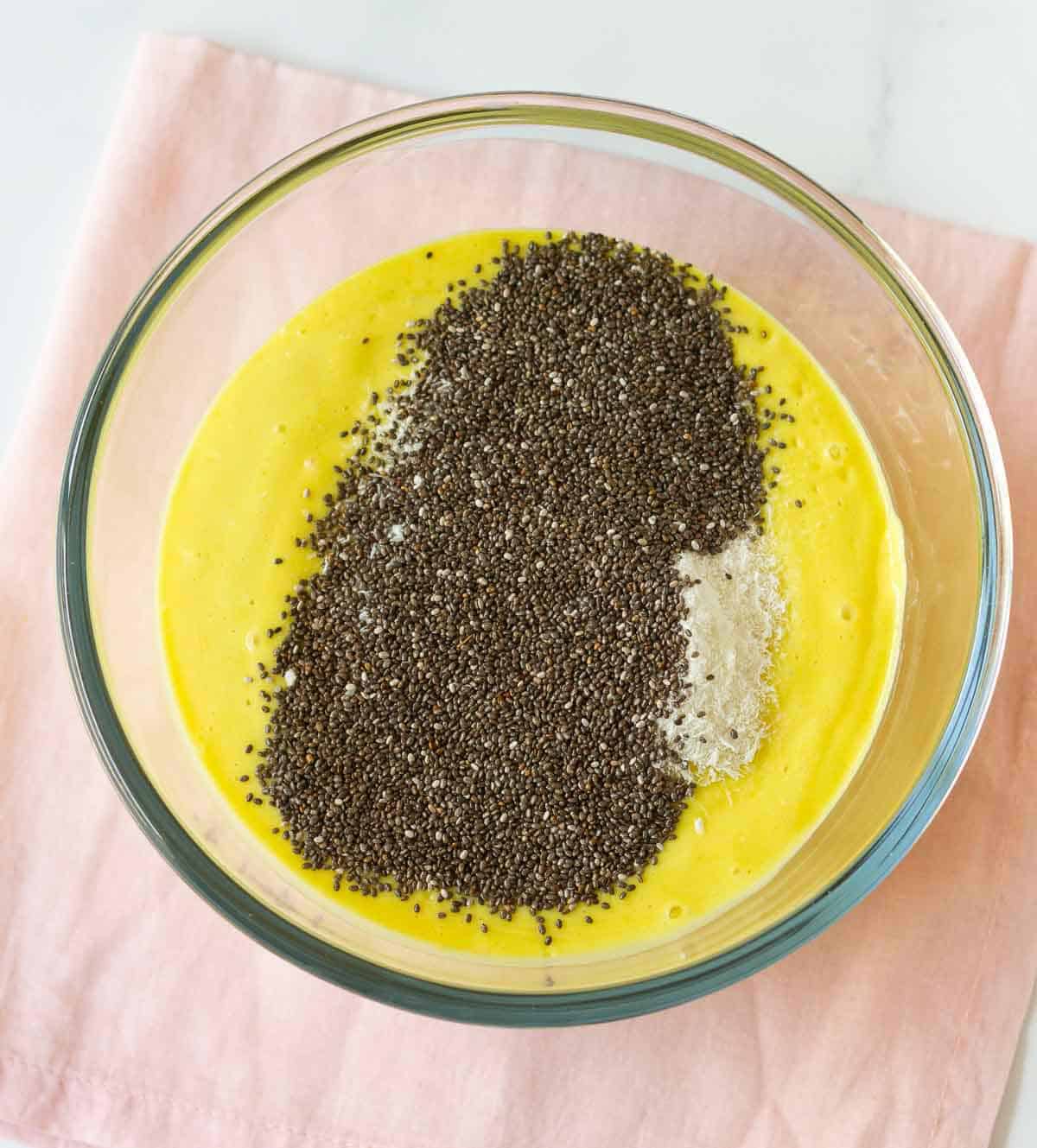 Desiccated coconut and chia seeds on top of mango mixture in a bowl.