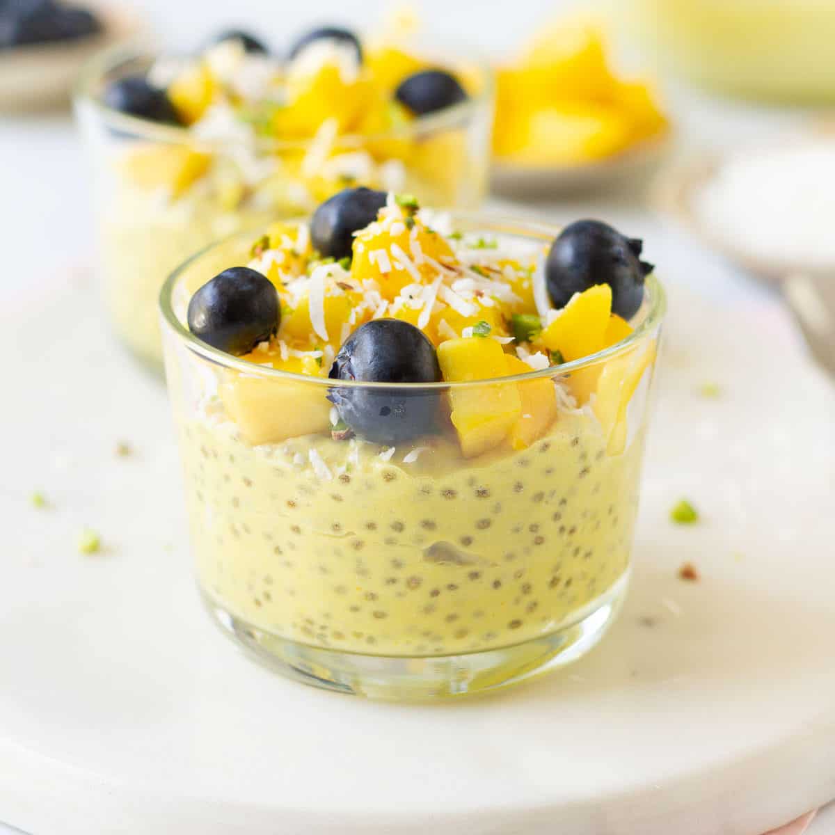 2 glasses of chia pudding with fruit toppings.