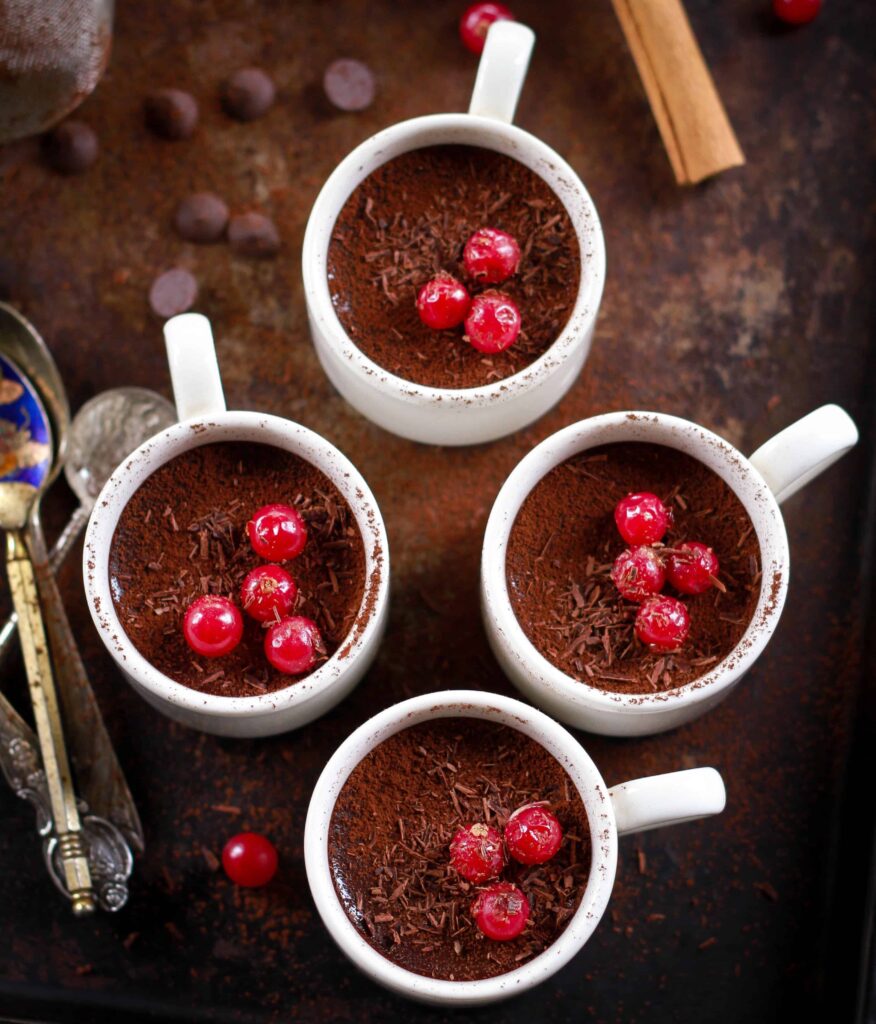 4 cups of easy chocolate pudding garnished with cherries and chocolate shavings.