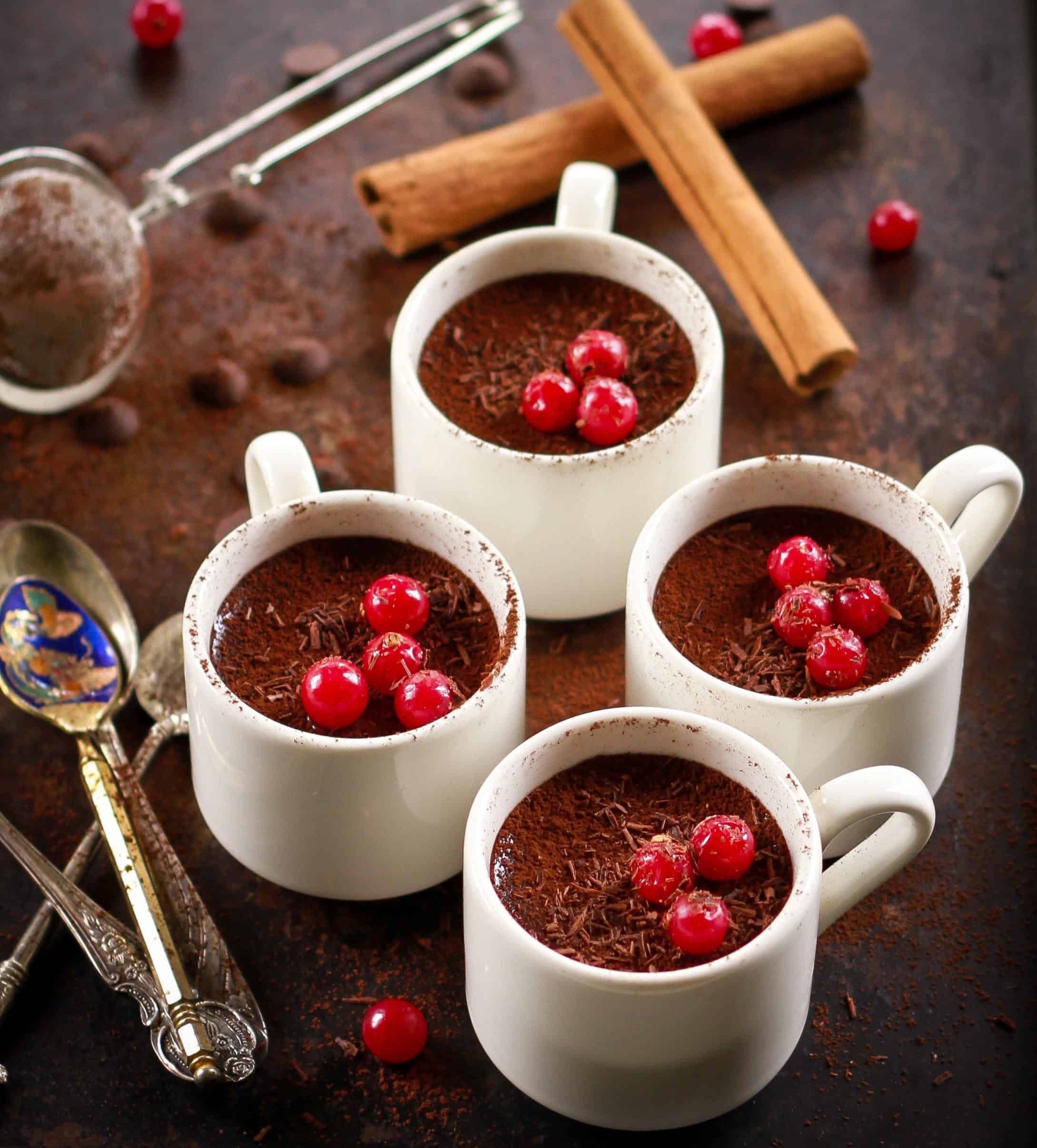 2-ingredient Chocolate Pudding in white cups with cinnamon sticks in the background.
