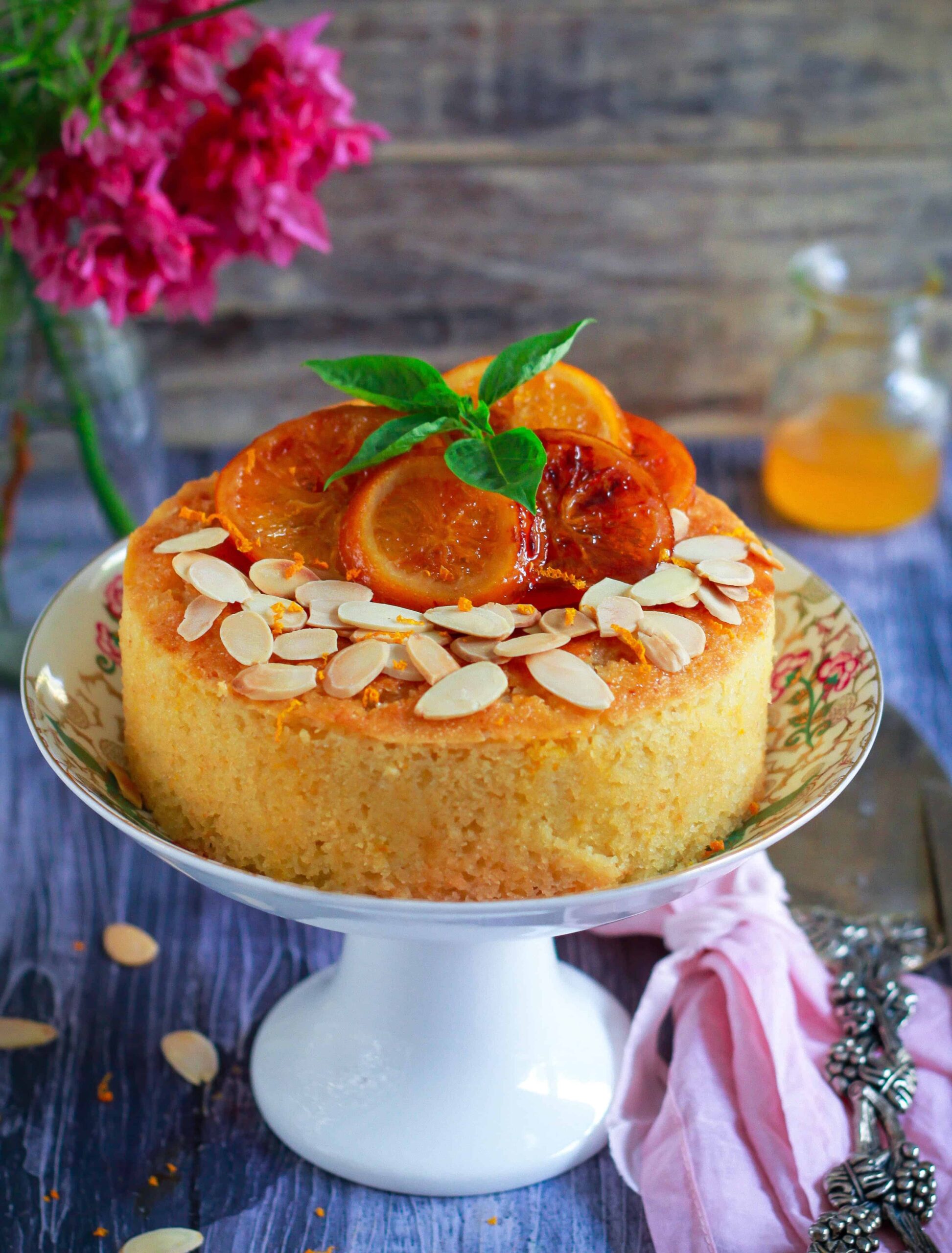 Orange Almond Cake topped with caramelized oranges on a cake stand.