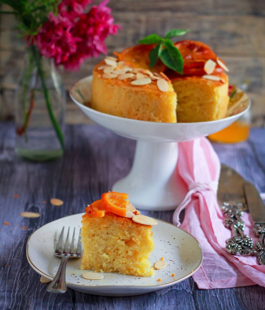 a slice of orange almond cake on a plate with a fork.