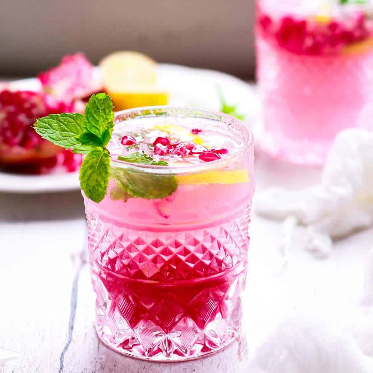 Pomegranate mojito in a glass garnished with mint and lime.
