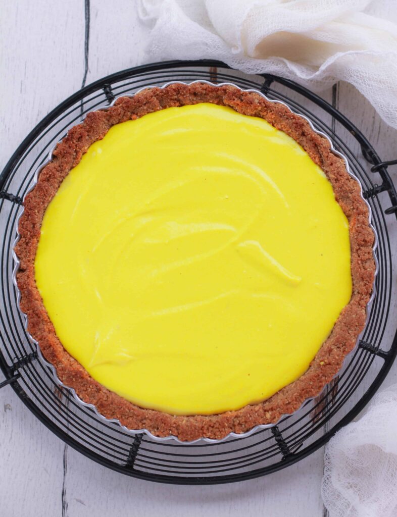 lemon tart in a tart pan on a trivet.