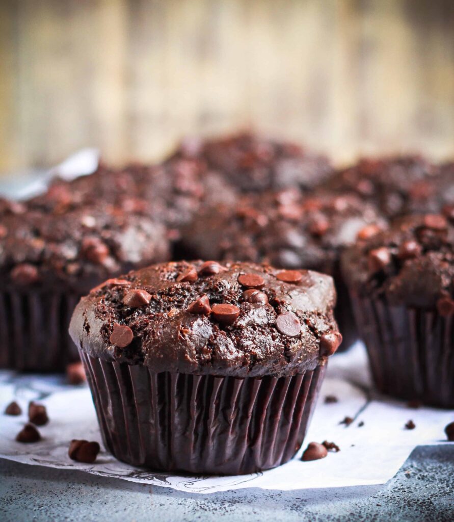 chocolate protein muffin on a surface with more muffins in the background.