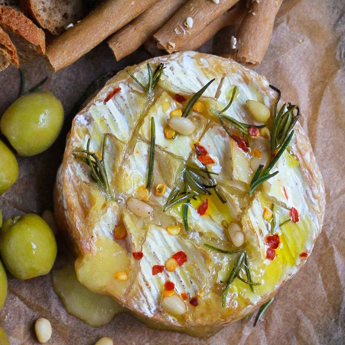 baked Camembert with olive oil and chili flakes on parchment paper.