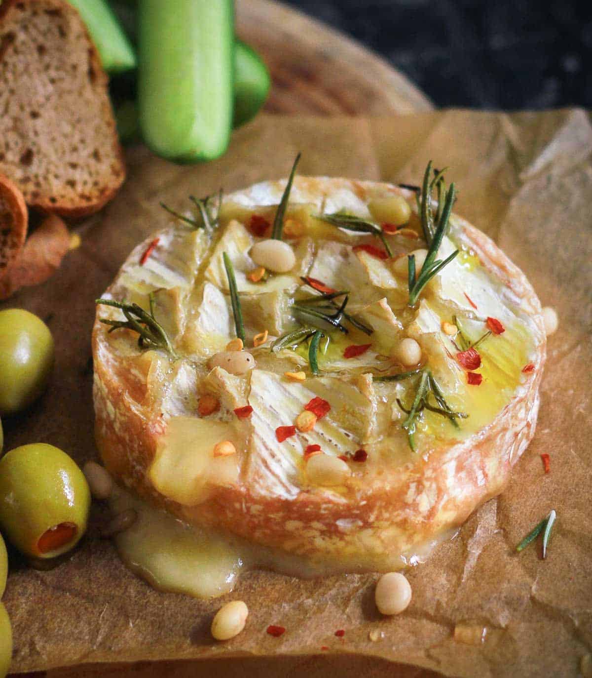 baked camembert with rosemary, olive oil, and chili flakes on baking paper.
