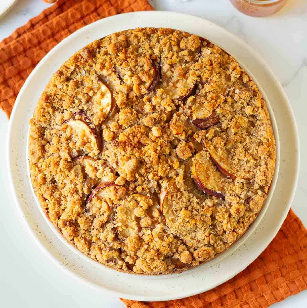 Apple crumb cake on a platter on top of an orange napkin.