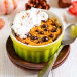pumpkin mug cake with chocolate chips and whipped cream on a plate.